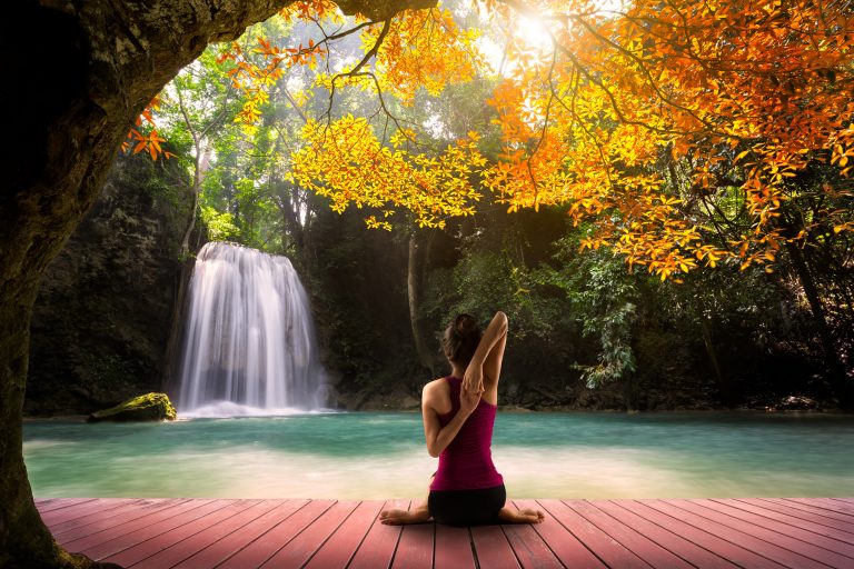 Woman practicing yoga near a waterfall